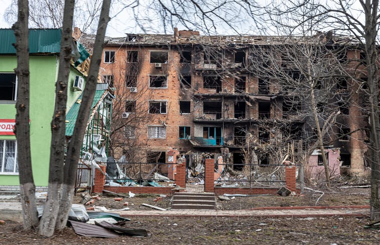 Un edificio de varios pisos destruido, alcanzado por bombas, con escombros esparcidos a su alrededor.