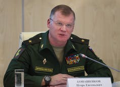 Un hombre con uniforme militar y gafas habla por un micrófono.