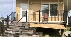 Una casa beige con un porche en ruinas