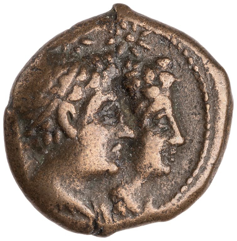 Una moneda de bronce que muestra dos caras grabadas.